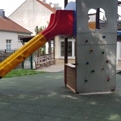Auf einem öffentlichen Kinderspielplatz wurden unter dem Spielturm mit Rutsche, Kletterwand und Hängebrücke WARCO Fallschutz-Puzzlematten in der Farbe Grasgrün verlegt.