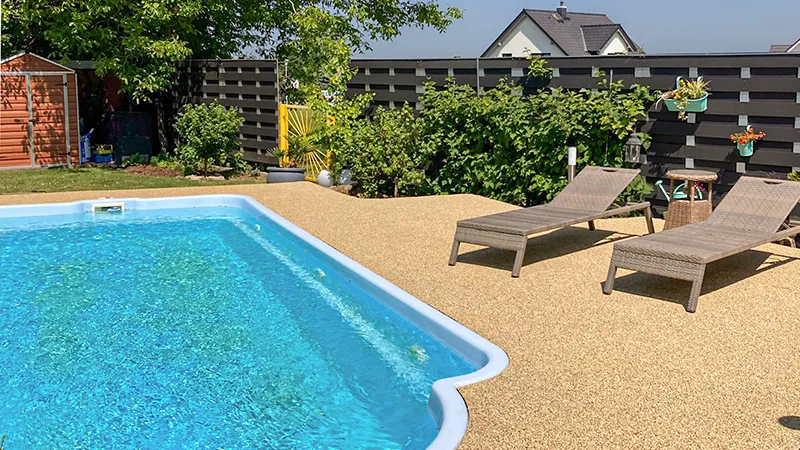 Blick auf eine Poolterrasse mit WARCO Poolumrandung im Farbdesign Travertin. Die elastischen Platten fügen sich zu einem nahezu fugenlosen, griffigen Plattenteppich zusammen; die Oberfläche wirkt barfußfreundlich und rutschhemmend – auch bei Nässe.