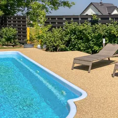 Blick auf eine Poolterrasse mit WARCO Poolumrandung im Farbdesign Travertin. Die elastischen Platten fügen sich zu einem nahezu fugenlosen, griffigen Plattenteppich zusammen; die Oberfläche wirkt barfußfreundlich und rutschhemmend – auch bei Nässe.
