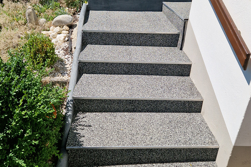 graue Außentreppemit WARCO-Treppenbelag führt am Haus vorbei Richtig Garten.