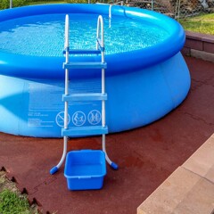 Auf einer Unterlage aus wasserdurchlässigen Poolplatten von WARCO steht ein Quick Up Pool dauerhaft und sauber. Außerhalb außerhalb der Badesaison kann die Fläche als Terrasse genutzt werden. runder Pool mit Leiter und braunem Belag