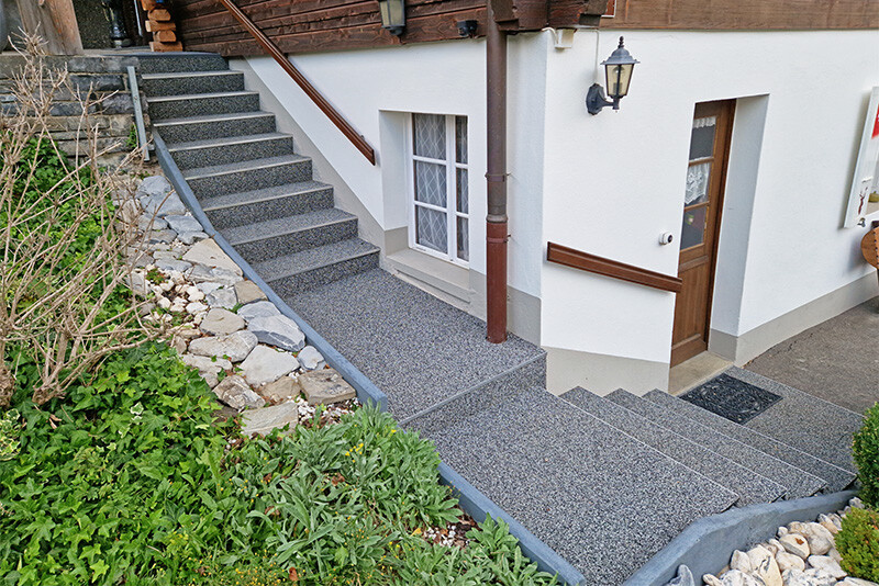 Le revêtement d'escalier antidérapant de WARCO en couleur Granit clair passe directement devant la maison dans les Alpes.