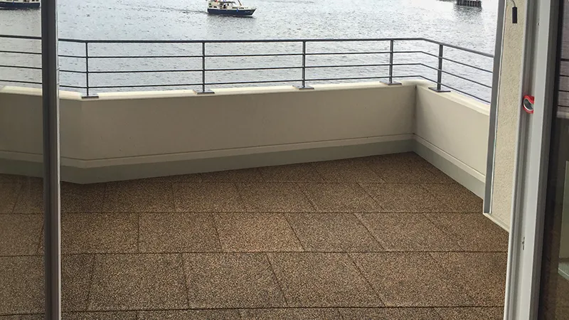 Balkon mit Blick aufs Wasser, verlegt mit WARCO Terrassenplatten Classic. Der Belag ist rutschhemmend, stoßdämpfend, pflegeleicht und frostbeständig – eine sichere und komfortable Fläche für Kinder, Senioren und Haustiere.