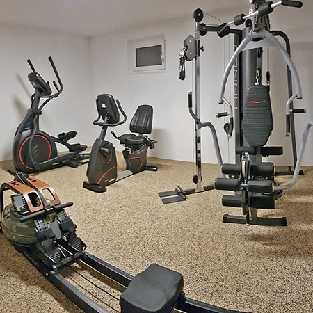 In diesem Homegym wurden elegante WARCO-Bodenschutzmatten mit EPDM-Oberfläche in Travertin-Optik verlegt. Die Platten sind durch eine formschlüssige Puzzleverzahnung dauerhaft miteinander verbunden und bieten so eine stabile und langlebige Bodenlösung. Der Raum ist mit einer Vielzahl von Trainingsgeräten ausgestattet, darunter ein Rudergerät, ein Crosstrainer, ein Ergometer und eine multifunktionale Kraftstation. Der WARCO Fitnessboden bietet eine angenehme und rutschfeste Oberfläche, die sich ideal für verschiedene Trainingsarten eignet. Darüber hinaus bietet der Boden hervorragende Dämpfungseigenschaften, die sowohl den Boden als auch die Gelenke der Trainierenden schonen.